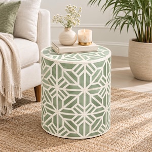 May include: A cylindrical side table featuring a sage green and white geometric inlay pattern. The table has a flat circular top surface and a smooth, straight-sided base, showcasing a repeating star-like design across its entire exterior.