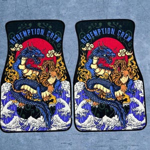 May include: A pair of rectangular car floor mats featuring a graphic illustration of a blue dragon and a tiger in combat. The design includes a red sun, stylised clouds, and blue ocean waves. The text REDEMPTION CREW is printed in blue at the top.