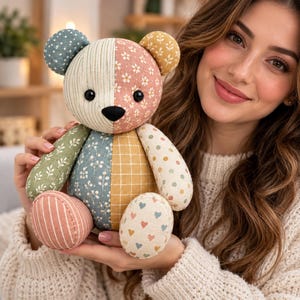 Könnte beinhalten: Ein Stoffteddybär aus verschiedenen Stoffstücken mit unterschiedlichen Mustern, darunter Blumenprints, Streifen, Karos und kleine Herzen in gedeckten Grün-, Blau-, Gelb- und Rosatönen, mit schwarzen Knopfaugen und einer schwarzen Nase.