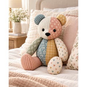 Pode incluir: Um urso de peluche patchwork feito de vários padrões de tecido, incluindo riscas, estampados florais, bolinhas e pequenos corações. O urso apresenta uma cara bicolor, olhos de botão pretos, um nariz preto e tons terra suaves.