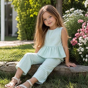 May include: A two-piece outfit consisting of a sleeveless peplum top and matching cropped trousers, both featuring a light mint green and white vertical striped pattern. The top has a round neckline and the trousers have a straight-leg cut.
