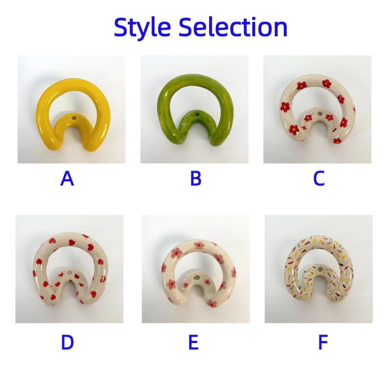 May include: Six ceramic wall hooks labeled A through F. A is solid yellow, B is solid green, C has red flowers, D has red hearts, E has pink flowers, and F has multi-colored sprinkles. Each hook has a curved, circular shape with a mounting hole.