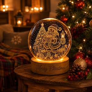 Könnte beinhalten: Eine kugelförmige Glaskugel mit einer geätzten Darstellung des Weihnachtsmanns, der ein Geschenk hält, sowie eines Weihnachtsbaums und einer Laterne. Sie steht auf einem runden Holzsockel mit der Gravur Merry Christmas und leuchtet.