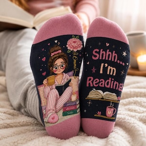May include: A pair of dark navy blue socks with pink cuffs and heels. The left sock features an illustration of a person with glasses reading a book, with the name Emma and a stack of books. The right sock displays the text Shhh... I'm Reading.