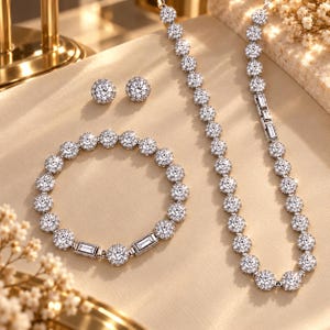 以下が含まれることがあります： ネックレス、ブレスレット、スタッドイヤリングのジュエリーセット。各ピースは、ハローデザインにセットされた丸い透明なファセットカットストーンが特徴で、ブレスレットとネックレスには長方形のバゲットストーンが組み込まれています。
