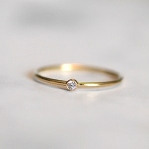 Op de afbeelding: Een eenvoudige gouden ring met een kleine diamant in het midden.