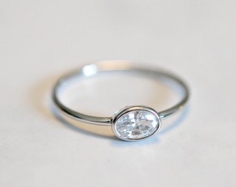 May include: A silver ring with a clear oval-shaped gemstone.