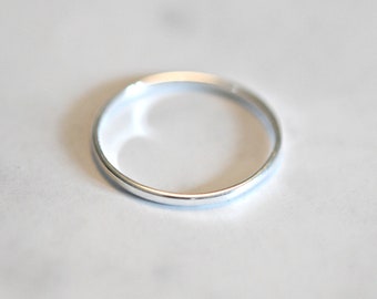 May include: A simple silver band ring.