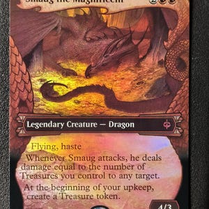 Puede incluir: Una carta coleccionable de Smaug the Magnificent con un dragón descansando sobre una pila de oro. El texto incluye Flying, haste y habilidades sobre fichas de Tesoro. La esquina inferior derecha muestra 4/3 y la izquierda M 0229.