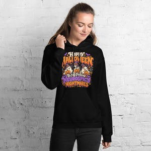 May include: A black hooded sweatshirt featuring a graphic print with the text Happy Halloween To My Fellow Neurospicy Nightmares. The design includes three white ghosts wearing purple witch hats and holding orange pumpkins with stars.
