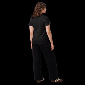 K&ouml;nnte beinhalten: Ein einfarbiges schwarzes T-Shirt mit kurzen &Auml;rmeln kombiniert mit einer passenden schwarzen Hose mit weitem Bein. Das Outfit wird durch braune Sneaker mit wei&szlig;en Schn&uuml;rsenkeln und wei&szlig;en Sohlen vor schwarzem Hintergrund erg&auml;nzt.