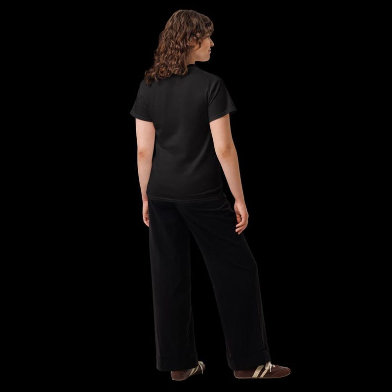 K&ouml;nnte beinhalten: Ein einfarbiges schwarzes T-Shirt mit kurzen &Auml;rmeln kombiniert mit einer passenden schwarzen Hose mit weitem Bein. Das Outfit wird durch braune Sneaker mit wei&szlig;en Schn&uuml;rsenkeln und wei&szlig;en Sohlen vor schwarzem Hintergrund erg&auml;nzt.