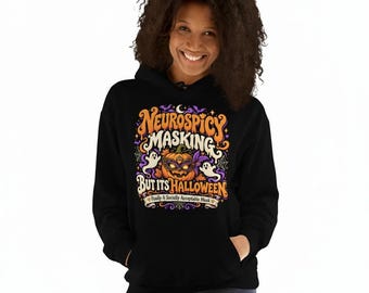 May include: A black hooded sweatshirt featuring a colorful graphic print with the text Neurospicy Masking But Its Halloween and Finally A Socially Acceptable Mask. The design includes a jack-o'-lantern wearing a purple mask, ghosts, and spiderwebs.