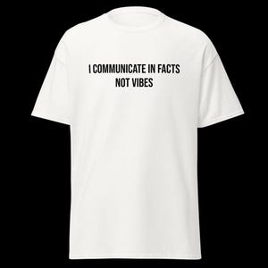 Peut inclure: Un t-shirt blanc &agrave; manches courtes avec le texte noir I COMMUNICATE IN FACTS NOT VIBES imprim&eacute; dans une police sans empattement sur la poitrine. Le v&ecirc;tement pr&eacute;sente un col rond classique et une coupe standard avec des manches courtes.