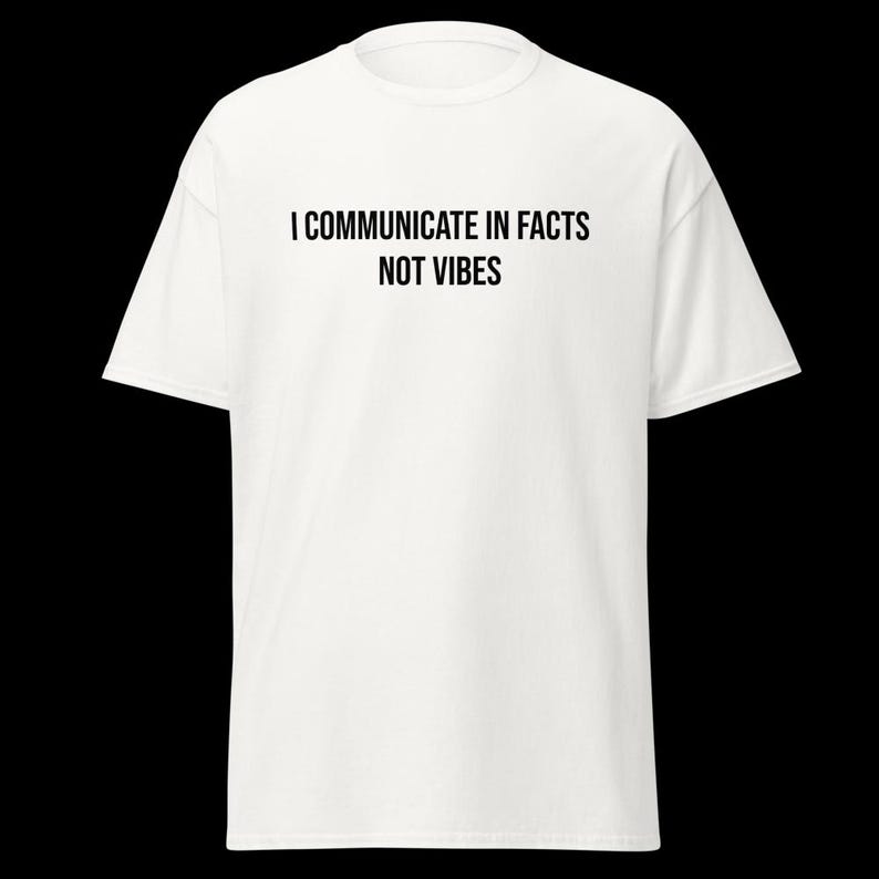 Peut inclure: Un t-shirt blanc &agrave; manches courtes avec le texte noir I COMMUNICATE IN FACTS NOT VIBES imprim&eacute; dans une police sans empattement sur la poitrine. Le v&ecirc;tement pr&eacute;sente un col rond classique et une coupe standard avec des manches courtes.