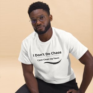 Op de afbeelding: Een wit T-shirt met korte mouwen en de zwarte opdruk I Don't Do Chaos I Just Clean Up Yours met een decoratieve zwarte swoosh-afbeelding onder de tekst. Het shirt heeft een ronde hals en een standaard pasvorm.