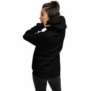 May include: A solid black hooded sweatshirt featuring long sleeves with ribbed cuffs and a matching ribbed hem. The garment includes a hood with a drawstring-free design and a plain, unpatterned back view, showcasing a simple and functional construction.