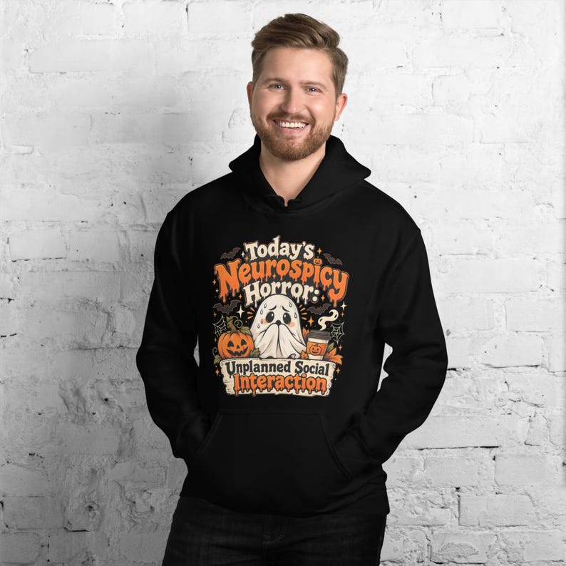 K&ouml;nnte beinhalten: Ein schwarzer Kapuzenpullover mit einem Grafikdruck und dem Text Today's Neurospicy Horror: Unplanned Social Interaction. Das Design zeigt ein wei&szlig;es Gespenst, einen orangefarbenen K&uuml;rbis und einen Kaffeebecher, umgeben von Flederm&auml;usen.