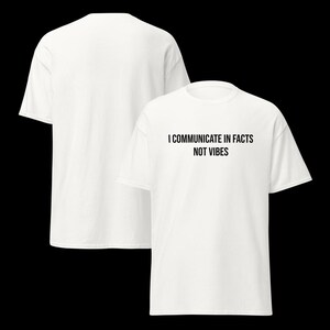Peut inclure: Un t-shirt blanc &agrave; manches courtes avec le texte noir I COMMUNICATE IN FACTS NOT VIBES imprim&eacute; sur la poitrine. Le v&ecirc;tement est pr&eacute;sent&eacute; sous deux angles, montrant un dos blanc uni et un col rond classique sur le devant de la pi&egrave;ce.