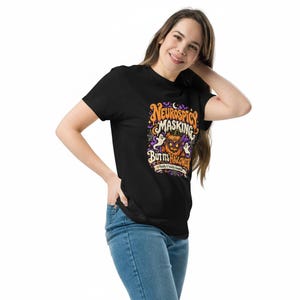 Pu&ograve; includere: Una t-shirt nera con una grafica colorata che riporta il testo "NEUROSPICY MASKING BUT ITS HALLOWEEN" e "Finally A Validly Creative". Il design include una zucca intagliata, due fantasmi bianchi, ragnatele e pipistrelli.