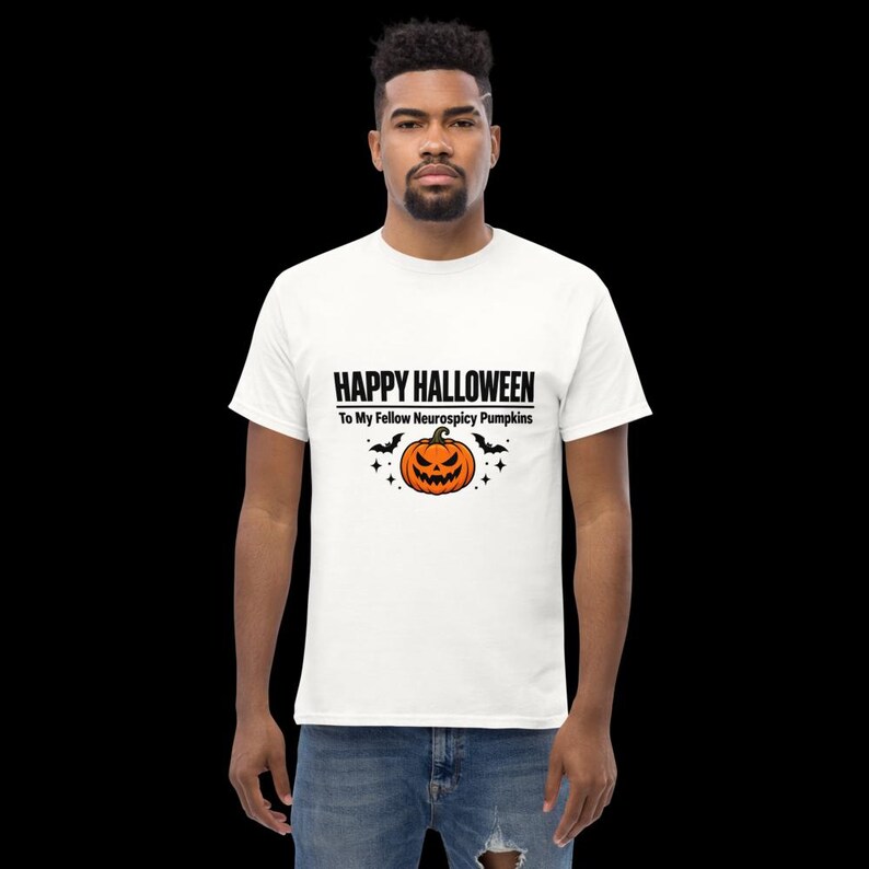 K&ouml;nnte beinhalten: Ein wei&szlig;es kurz&auml;rmeliges T-Shirt mit einem Aufdruck, der den Text HAPPY HALLOWEEN To My Fellow Neurospicy Pumpkins &uuml;ber einer orangefarbenen K&uuml;rbis-Illustration mit zwei kleinen schwarzen Flederm&auml;usen und Sternakzenten zeigt.