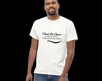 Op de afbeelding: Een wit T-shirt met korte mouwen en een ronde hals, voorzien van zwarte tekst op de borst met de tekst I Don't Do Chaos I Just Clean Up Yours, vergezeld van een decoratieve krul en een gebogen lijn onder de tekst.
