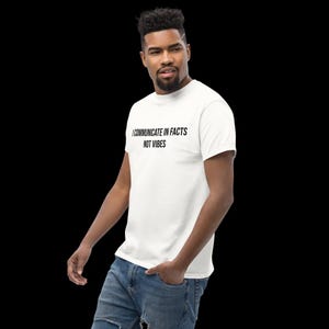 Peut inclure: Un t-shirt blanc &agrave; manches courtes avec le texte noir "I COMMUNICATE IN FACTS NOT VIBES" imprim&eacute; sur la poitrine. Le v&ecirc;tement est associ&eacute; &agrave; un jean bleu, pr&eacute;sentant un col rond standard et une finition en tissu blanc uni et propre.