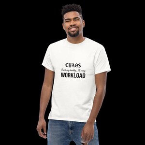 May include: A white short-sleeved t-shirt featuring black text on the chest that reads: CHAOS Isn't my hobby, It's my WORKLOAD. The shirt is paired with blue denim jeans, creating a casual look with a clear, bold graphic print on the front.