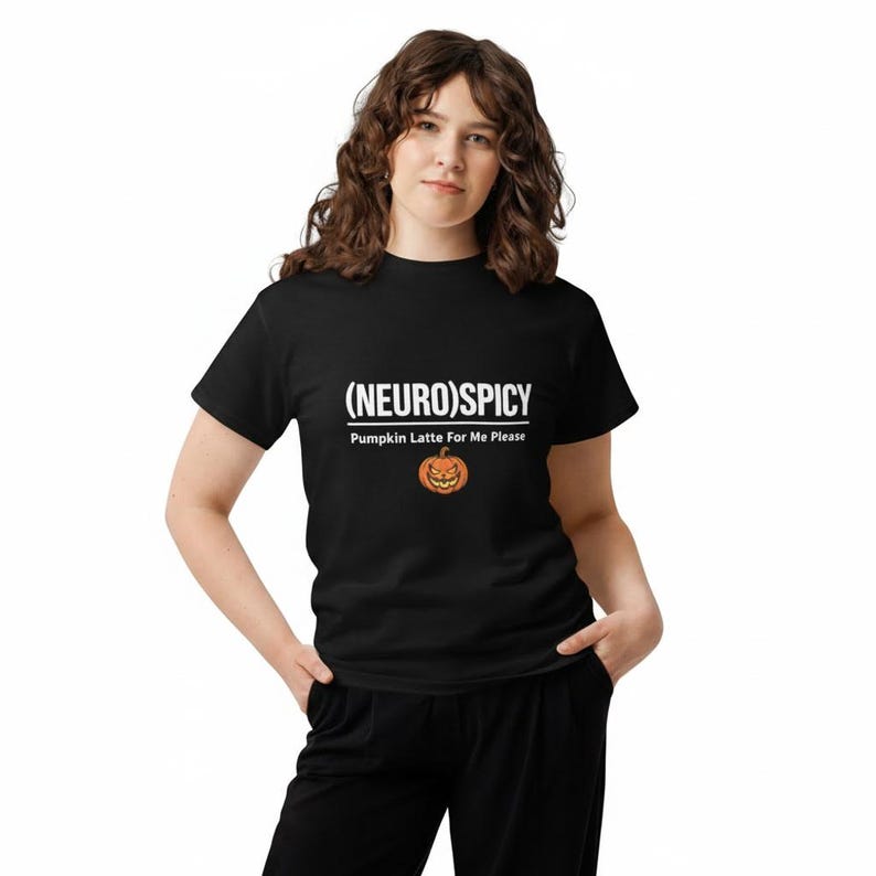 May include: A black short-sleeved t-shirt featuring the white text (NEURO)SPICY and Pumpkin Latte For Me Please, accompanied by a small orange jack-o'-lantern graphic with a mischievous facial expression centered on the chest area.