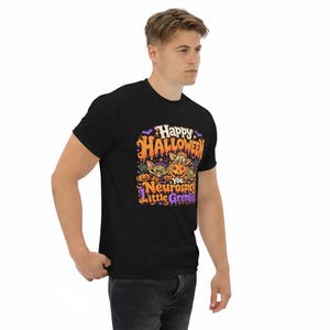 May include: A black t-shirt featuring a colorful Halloween-themed graphic with the text "Happy Halloween You Neurospicy Little Gremlins". The design includes illustrations of small green creatures, orange pumpkins, purple bats, and spiderwebs.