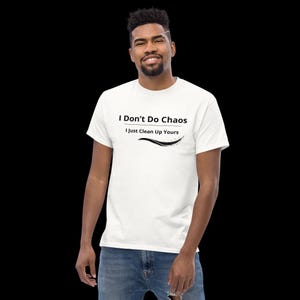 Op de afbeelding: Een wit t-shirt met korte mouwen voorzien van de zwarte gedrukte tekst I Don't Do Chaos, gevolgd door de tekst I Just Clean Up Yours, en een zwart grafisch swoosh-ontwerp onder de tekst, alles gecentreerd op de borst van het kledingstuk.