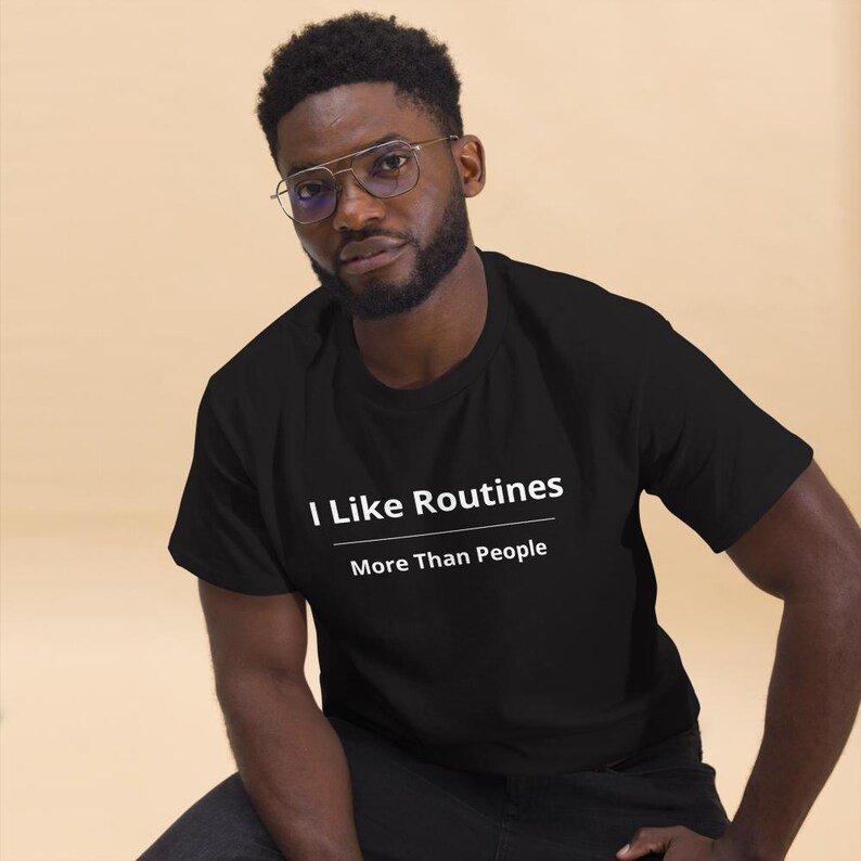 K&ouml;nnte beinhalten: Ein schwarzes Kurzarm-T-Shirt mit dem wei&szlig;en Text "I Like Routines" &uuml;ber einer horizontalen Linie und dem darunter gedruckten Text "More Than People". Das T-Shirt hat einen Rundhalsausschnitt und eine Standardpassform aus einfarbigem Stoff.