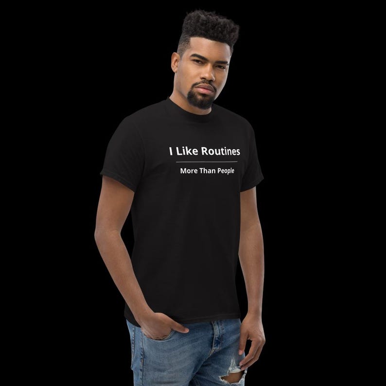 K&ouml;nnte beinhalten: Ein schwarzes Kurzarm-T-Shirt mit dem wei&szlig;en Text "I Like Routines" &uuml;ber einer horizontalen Linie und dem Text "More Than People" direkt unter der Linie. Das T-Shirt hat einen Rundhalsausschnitt und ein klassisches Design.