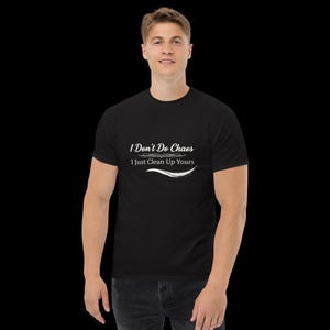 May include: A black short-sleeved t-shirt featuring white text printed on the chest that reads, I Don't Do Chaos, I Just Clean Up Yours, accompanied by a decorative white flourish design positioned between the two lines of text.
