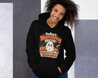 May include: A black hooded sweatshirt featuring a graphic print with the text Today's Neurospicy Horror: Unplanned Social Interaction. The design includes a white ghost, an orange pumpkin, a coffee cup, bats, and spiderwebs.