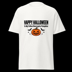 K&ouml;nnte beinhalten: Ein wei&szlig;es Kurzarm-T-Shirt mit einem Aufdruck, der den Text "HAPPY HALLOWEEN To My Fellow Neurospicy Pumpkins" in schwarzer Schrift zeigt, zentriert &uuml;ber einer orangefarbenen K&uuml;rbis-Illustration, flankiert von zwei schwarzen Flederm&auml;usen.