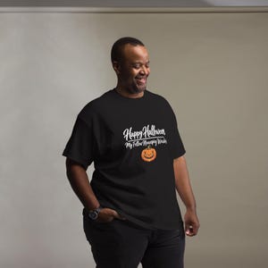 May include: A black short-sleeved t-shirt featuring white text that reads Happy Halloween My Fellow Neurospicy Weirdos, accompanied by a graphic of an orange jack-o'-lantern with a jagged, smiling face centered below the printed text.