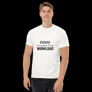 May include: A white short-sleeved t-shirt featuring black text printed on the chest. The text reads "CHAOS Isn't my hobby, It's my WORKLOAD" in a combination of gothic and sans-serif fonts. The shirt has a crew neckline and a standard fit.