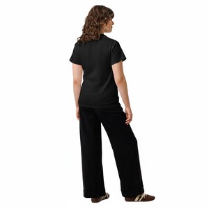 May include: A solid black short-sleeved t-shirt paired with matching black wide-leg trousers. The outfit is completed with brown and white low-top sneakers. The clothing set is presented from a rear-facing perspective against a plain white background.