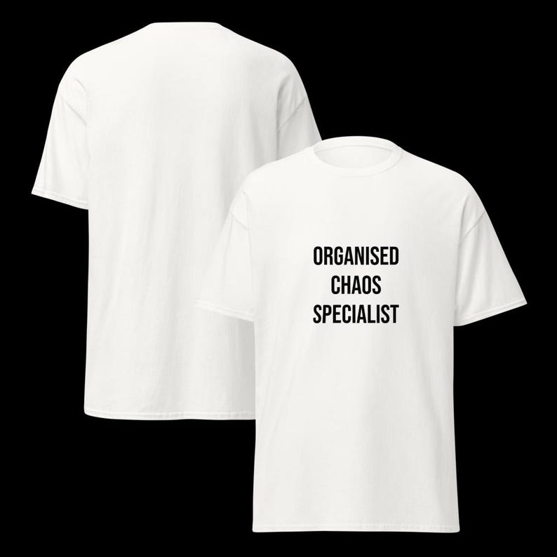 May include: A white short-sleeved t-shirt featuring the black text "ORGANISED CHAOS SPECIALIST" printed on the front chest area. The garment has a crew neckline and a standard fit, shown from both the front and back views against a black background.