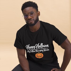 May include: A black short-sleeved t-shirt featuring the white text Happy Halloween My Fellow Neurospicy Weirdos above a graphic of an orange jack-o'-lantern pumpkin with a carved face and glowing yellow eyes.