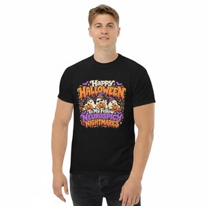 May include: A black short-sleeve t-shirt featuring a colourful graphic print with three ghosts wearing purple witch hats and holding orange pumpkins. The text reads Happy Halloween To My Fellow Neurospicy Nightmares in orange and purple lettering.