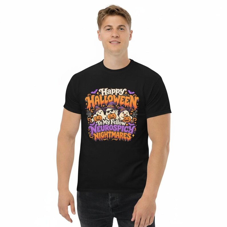 May include: A black short-sleeve t-shirt featuring a colourful graphic print with three ghosts wearing purple witch hats and holding orange pumpkins. The text reads Happy Halloween To My Fellow Neurospicy Nightmares in orange and purple lettering.