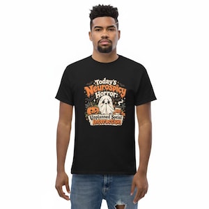 Könnte beinhalten: Ein schwarzes Kurzarm-T-Shirt mit einem Grafikdruck und dem Text "Today's Neurospicy Horror: Unplanned Social Interaction". Das Design zeigt ein weißes Gespenst, einen orangefarbenen Kürbis, einen Kaffeebecher, Fledermäuse und Spinnenweben.