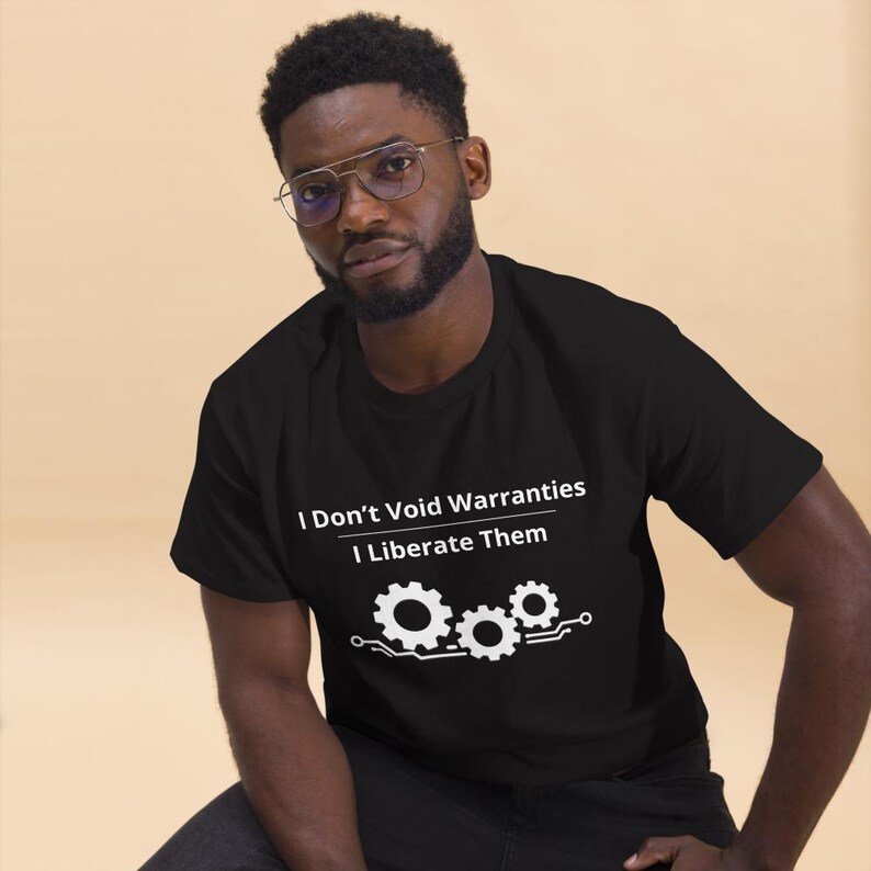 May include: A black short-sleeved t-shirt featuring white text that reads I Don't Void Warranties I Liberate Them, accompanied by a graphic of three interconnected gears and circuit board lines printed on the front of the garment.