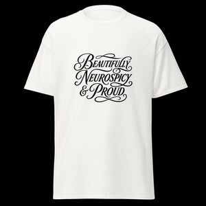 K&ouml;nnte beinhalten: Ein wei&szlig;es T-Shirt mit kurzen &Auml;rmeln und schwarzem, kursivem Text in der Mitte der Brust, der Beautifully Neurospicy & Proud lautet. Das Kleidungsst&uuml;ck hat einen klassischen Rundhalsausschnitt und eine Standardpassform mit klarem Design.