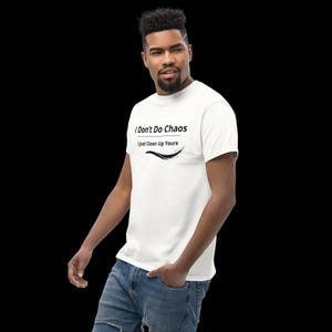 Op de afbeelding: Een wit T-shirt met korte mouwen voorzien van de zwarte tekst I Don't Do Chaos I Just Clean Up Yours met een kleine zwarte grafische versiering eronder. Het shirt heeft een ronde hals en wordt gedragen met een blauwe spijkerbroek.
