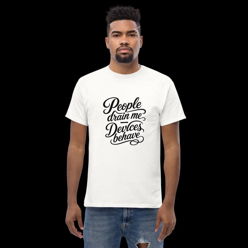 Op de afbeelding: Een wit T-shirt met korte mouwen en zwarte cursieve tekst op de borst die luidt People drain me, Devices behave. Het shirt heeft een ronde hals en een standaard pasvorm, gemaakt van effen witte stof met opvallende zwarte letters.