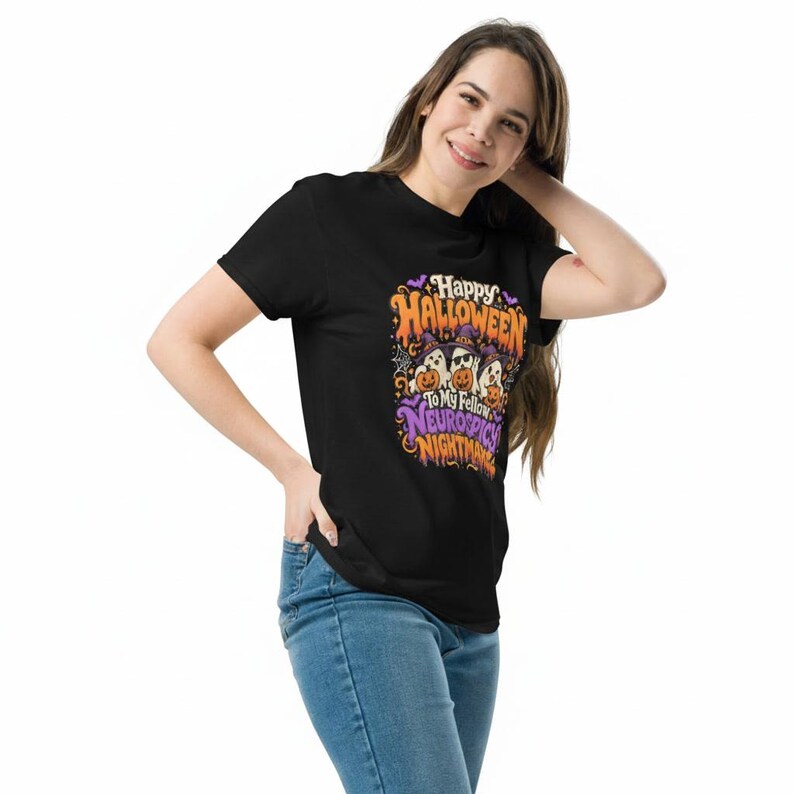 May include: A black short-sleeved t-shirt featuring a colourful graphic print with the text Happy Halloween to my fellow neurospicy nightmares, depicting three ghosts wearing witch hats and holding orange jack-o'-lanterns with bats and spiderwebs.