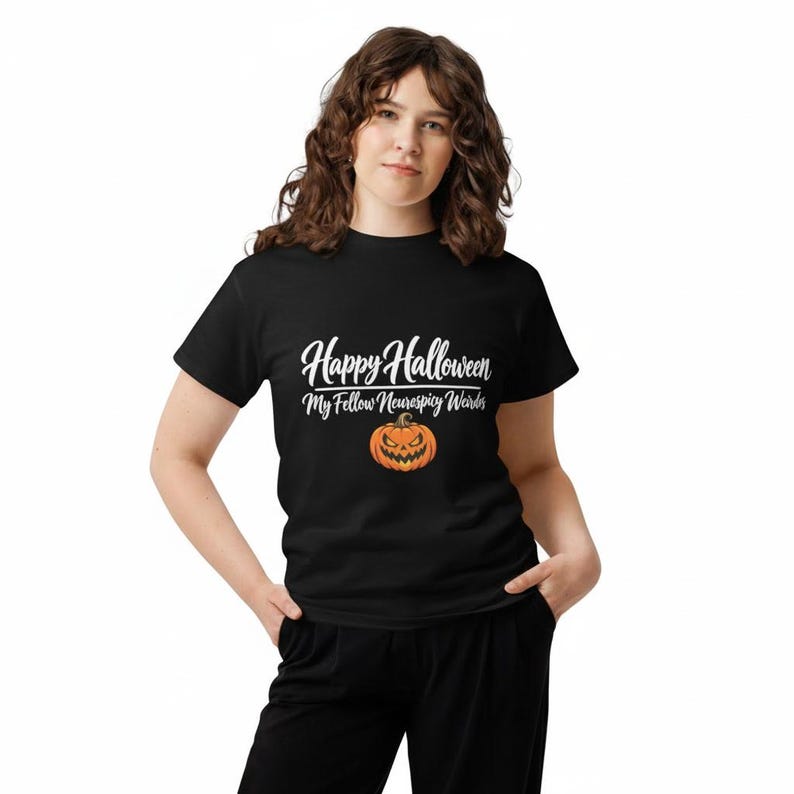 May include: A black short-sleeved t-shirt featuring white text that reads Happy Halloween My Fellow Neurospicy Weirdos above an orange jack-o'-lantern graphic with a jagged, menacing grin and triangular eyes centered on the chest area.